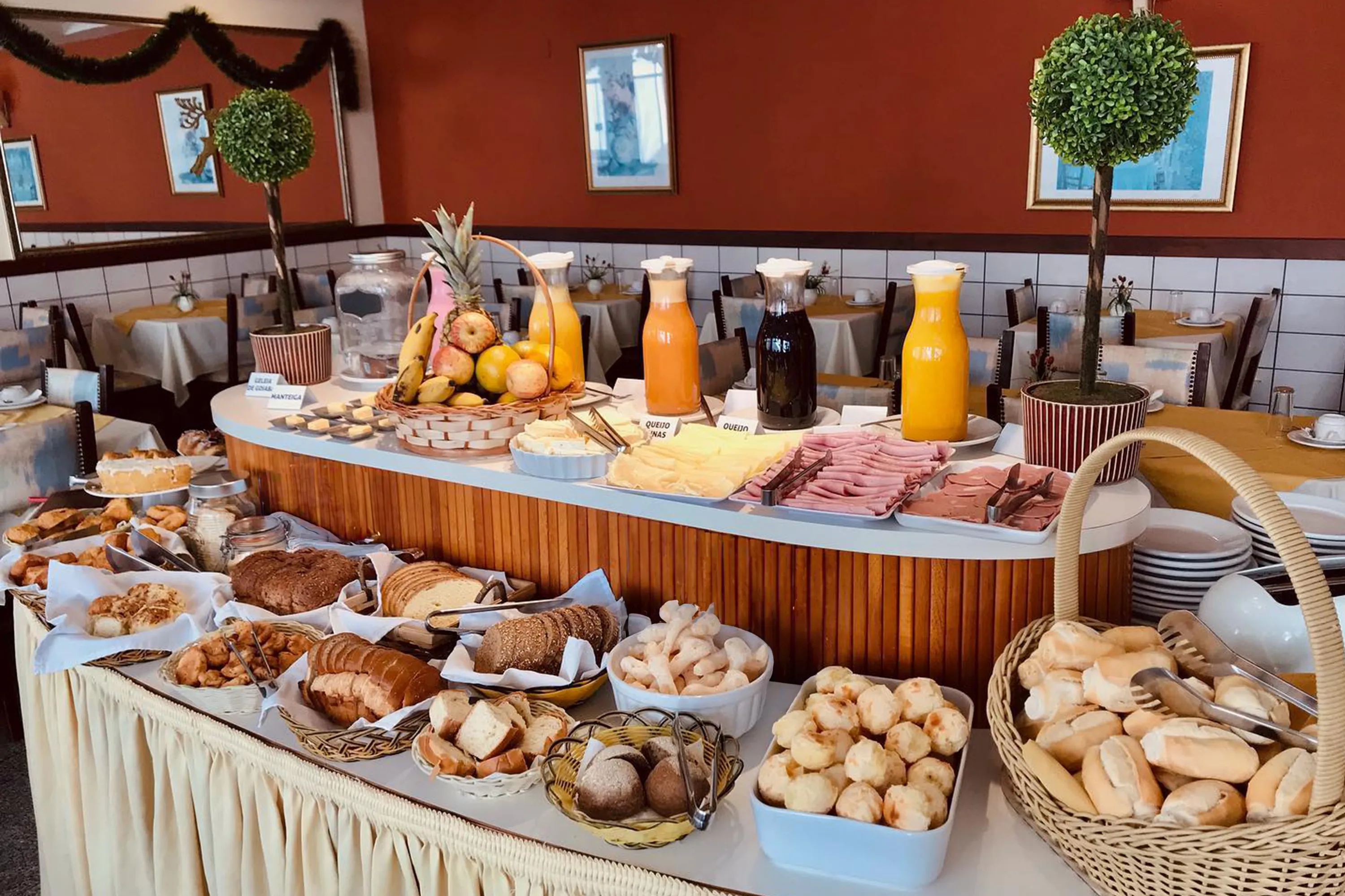 café da manhã bem servido no hotel solaris em São Lourenço, com diversos pães, frios, sucos e pão de queijo