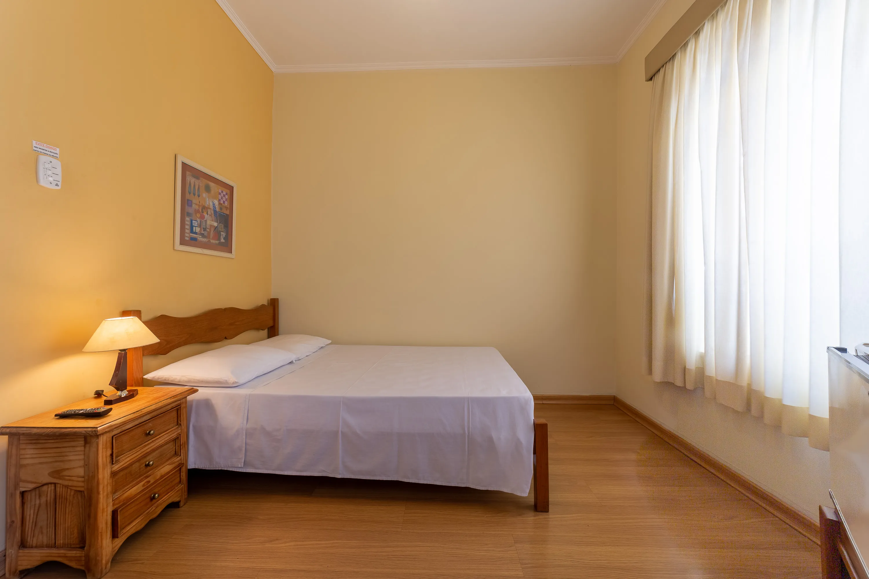 foto de quarto standard com ventilador, com uma cama de casal, com paredes em tons pastéis, teto branco com sanca de gesso, piso laminado de madeira