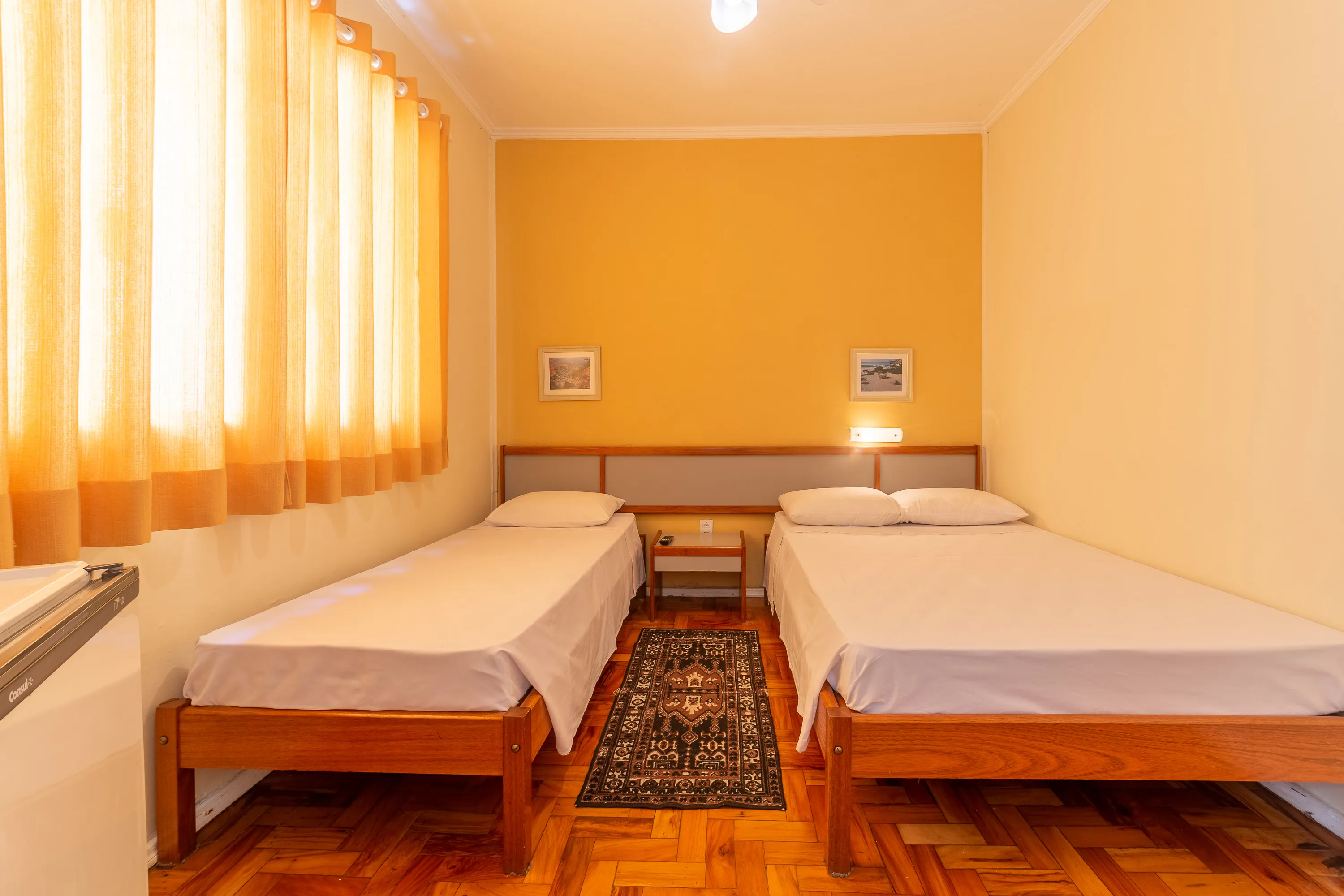 foto de quarto com ventilador com uma cama de casal e uma cama de solteiro, com paredes em tons pastéis, teto branco e piso de taco